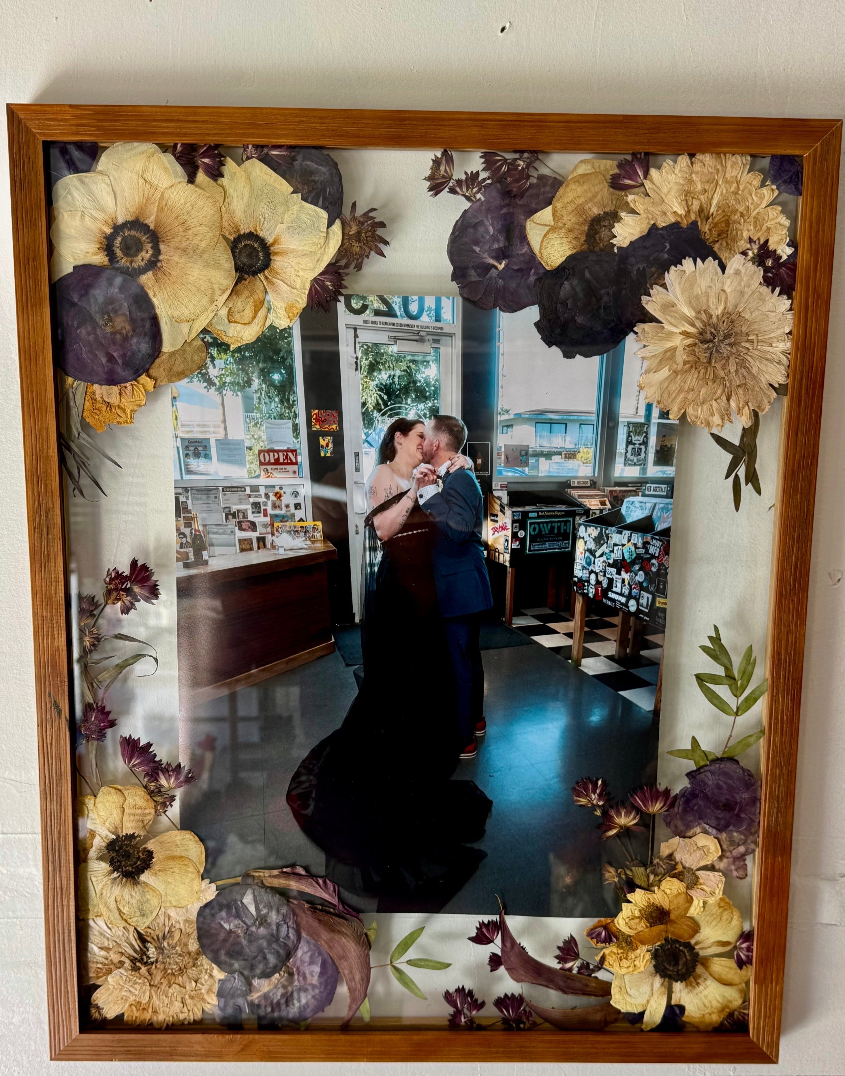 Framed photograph of a couple kissing in a kitchen with floral decorations.